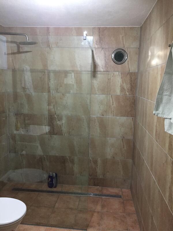 Blick in die fertige Dusche mit Glaswand und Wandablage.