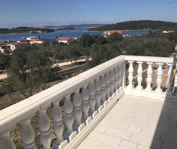 Terrasse mit Steinbalustrade, Blick über Olivenhäine auf das Meer und vorgelagerte Inseln.