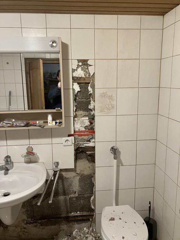 Demontierter Waschtisch und geöffnete Vorwandinstallation nach dem Wasserschaden.